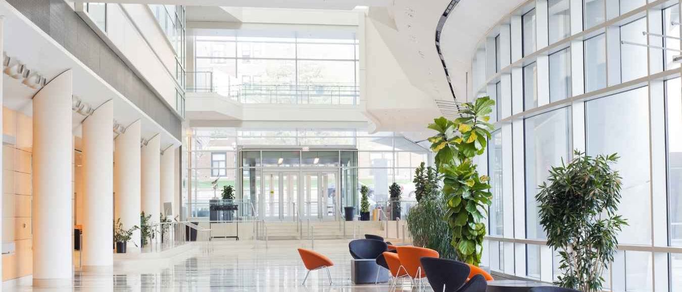 Bright corporate atrium with glass, white columns and orange and navy chairs