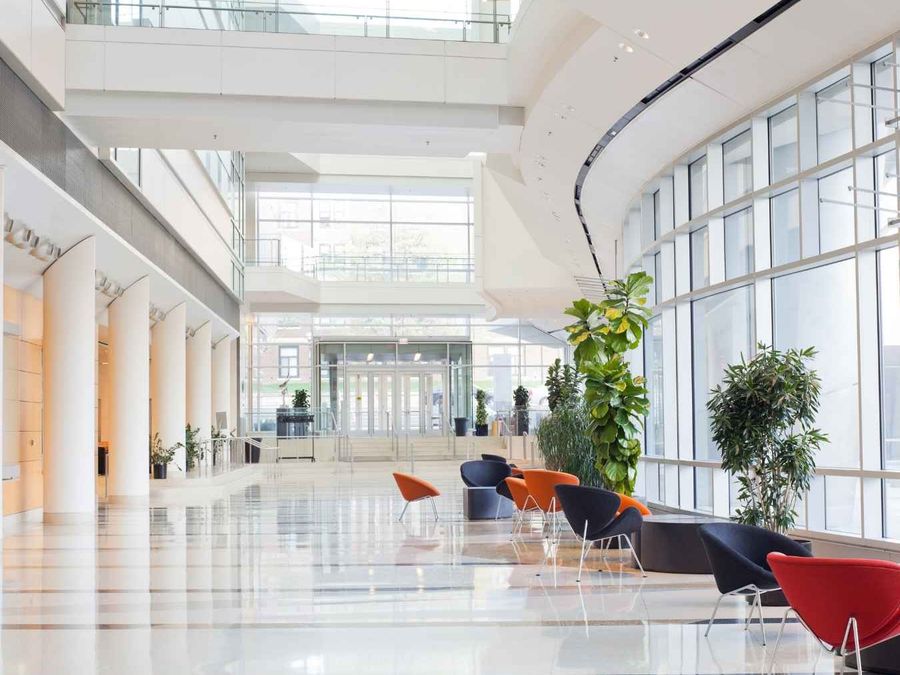 Bright corporate atrium with glass, white columns and orange and navy chairs